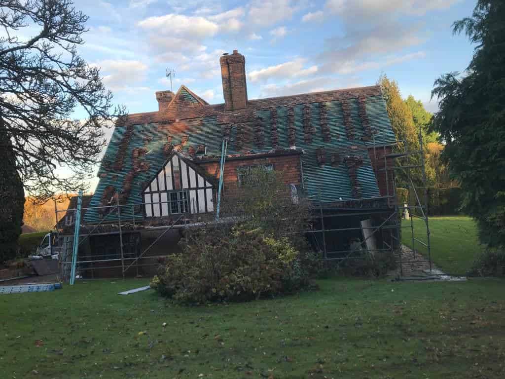 This is a photo of a large country house where the roof has been stripped, and the felt and batten replaced and new tiling is now being fitted.