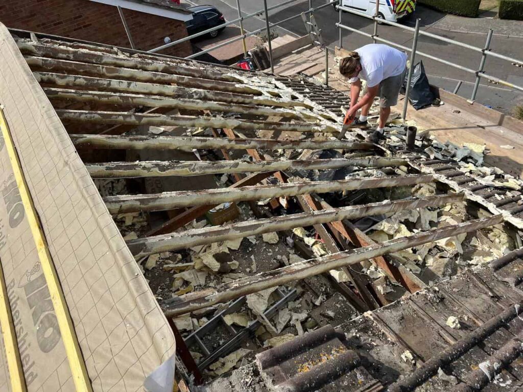 This is a photo of a very old pitched roof which is being stripped on one side, and the other is just felt and batten The complete roof is being replaced as it is in very poor condition.