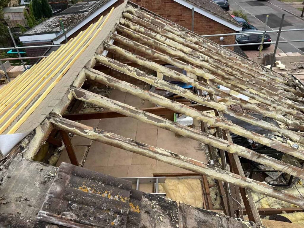 This is a photo of a very old pitched roof which is being stripped on one side, and the other is just felt and batten The complete roof is being replaced as it is in very poor condition.