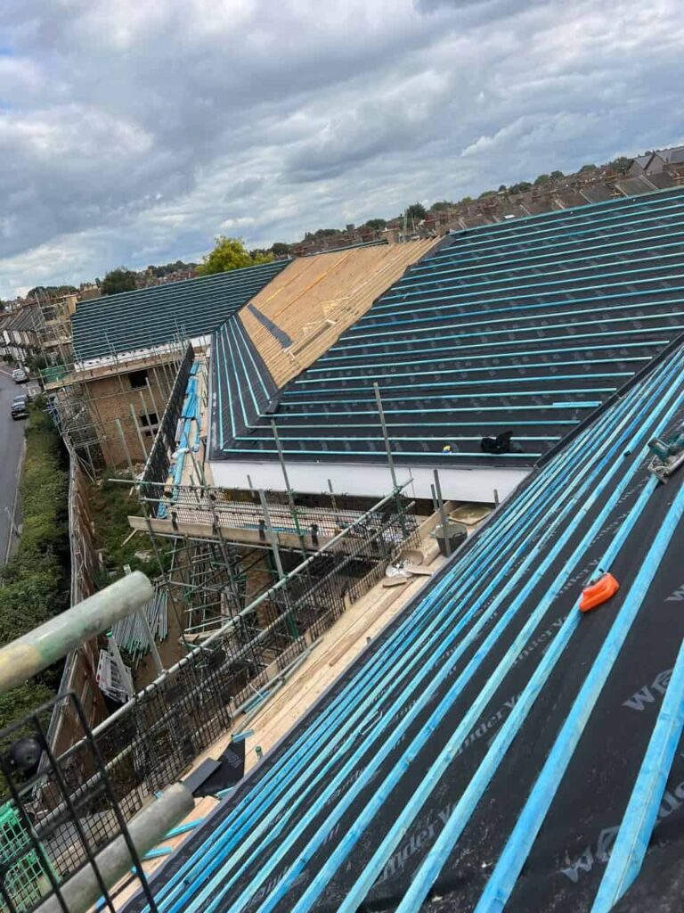 This is a photo of a new roof being constructed. The vast proportion is felt and batten, and there is a section that is exposed rafters. The roof is waiting for the new tiles to be installed