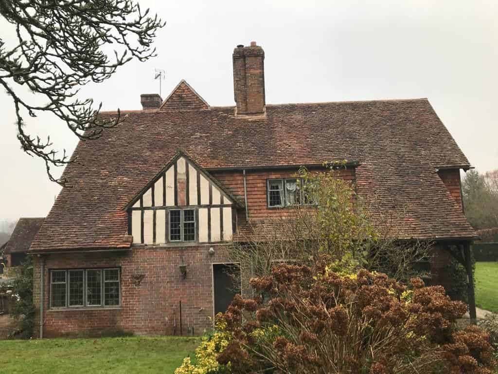 This is a photo of a large country house with a tiled roof which is in need of a re-roof. There are missing tiles and the roof is generally in poor condition